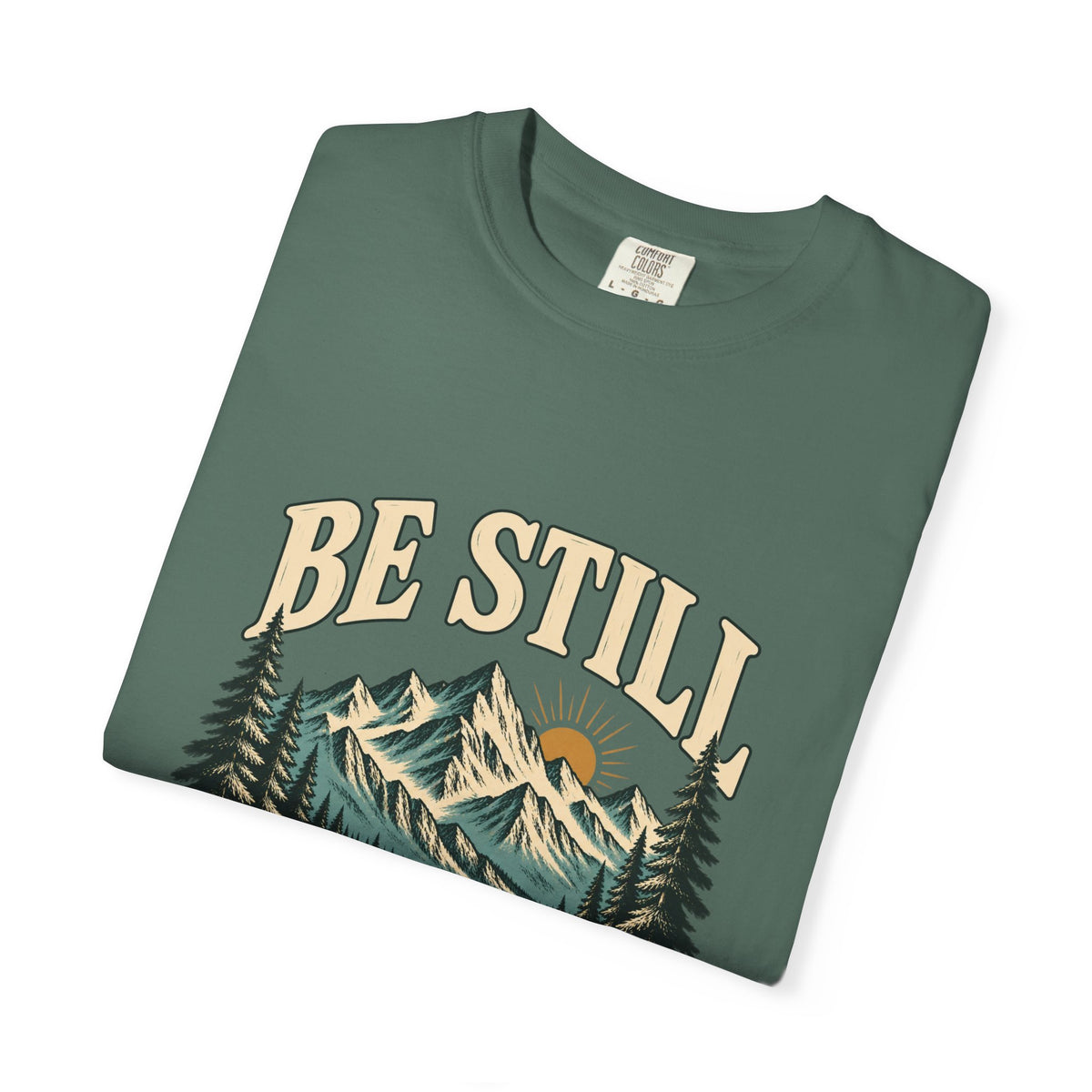 Folded Blue Spruce Be Still mountain T-shirt showing the front artwork and Comfort Colors label.