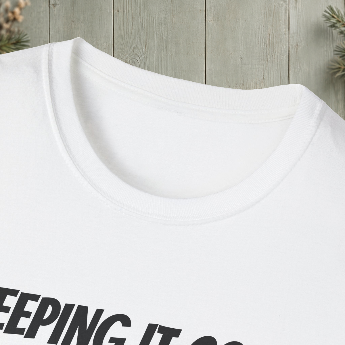 White Keeping It Cool T-Shirt collar-detail view with original antler artwork on a muted woodland background.